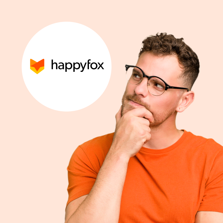 A man in glasses and an orange shirt looks thoughtfully at the HappyFox logo, possibly considering HappyFox alternatives for customer service solutions.